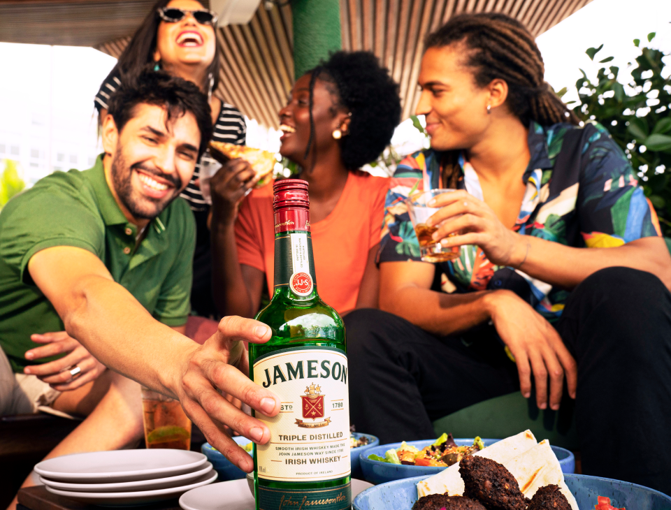 Friends laughing and enjoying a bottle of Jameson Irish Whiskey together