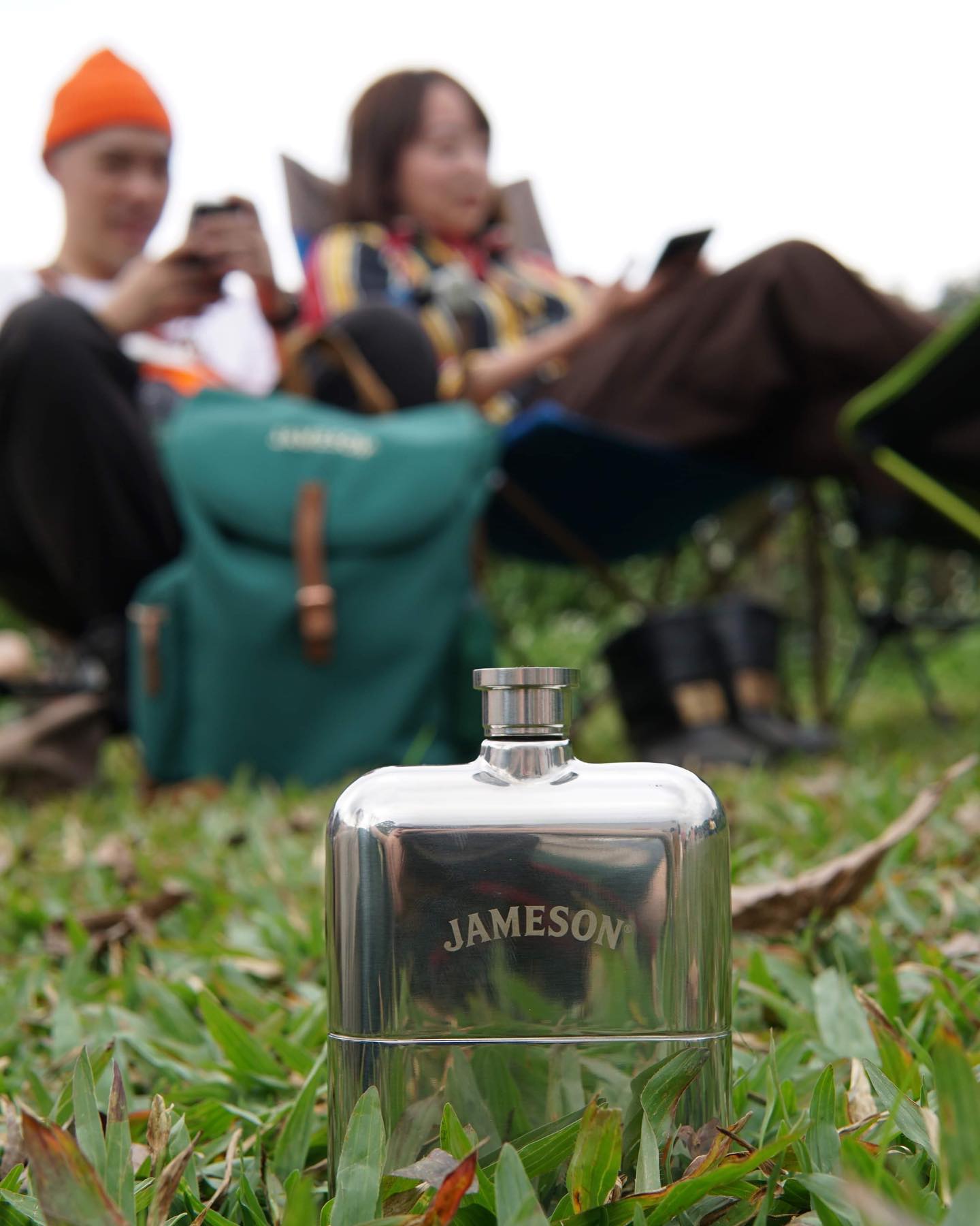 Jameson branded hip flask being used while camping