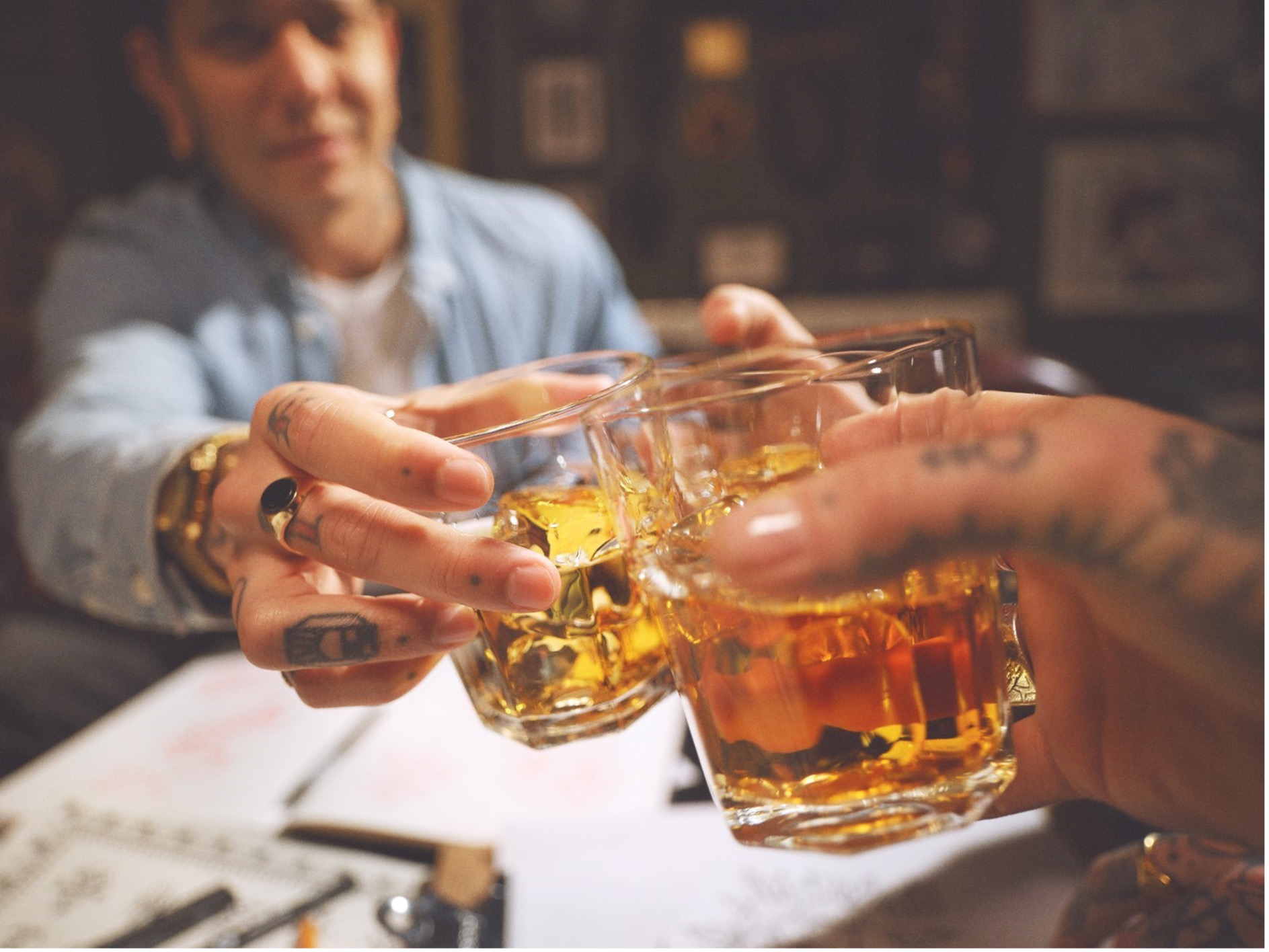 Two friends doing a cheers over whiskey on ice
