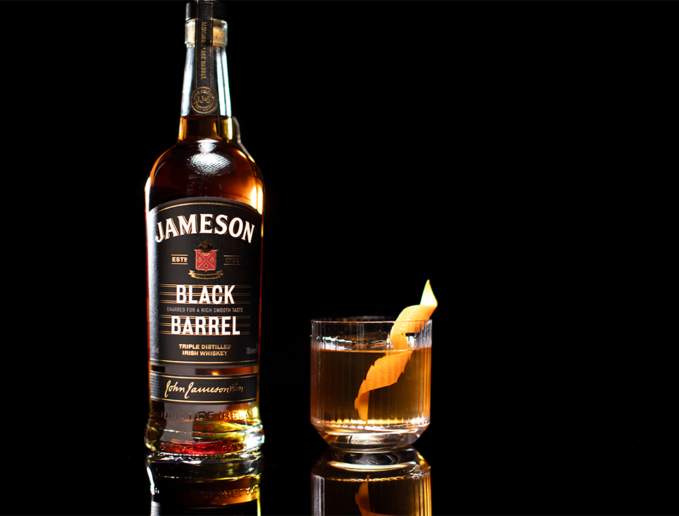 A bottle of Jameson Black Barrel standing alongside an old-fashioned cocktail