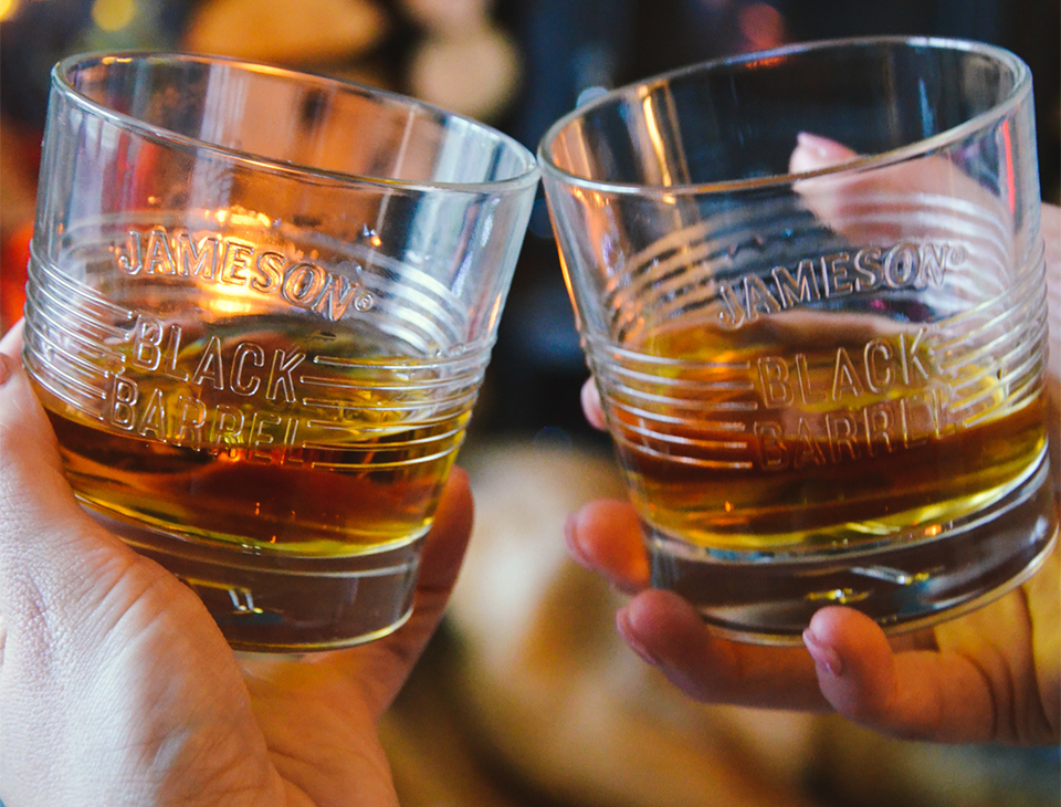 Two people completing a cheers with a neat Jameson Black Barrel serving each