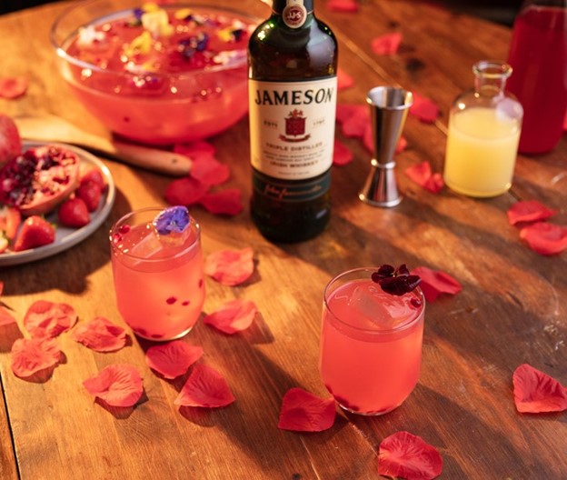 two romeo punch cocktails made with jameson irish whiskey and garnished with edible flowers