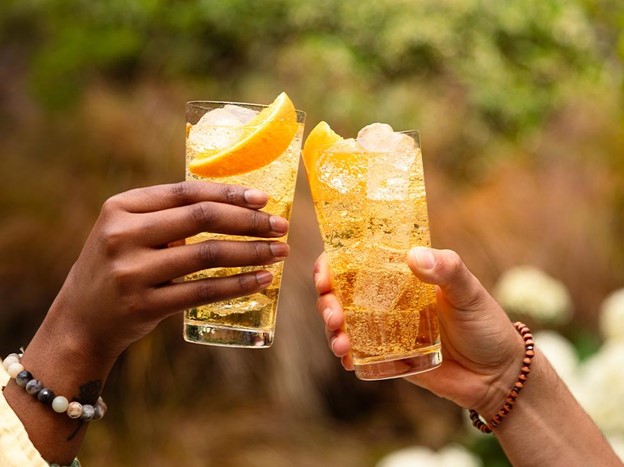 two friends doing a cheers over two whiskey cocktails