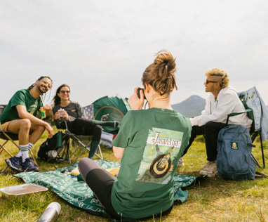 Image of a group of young people camping and wearing some camping green Jameson t-shirts